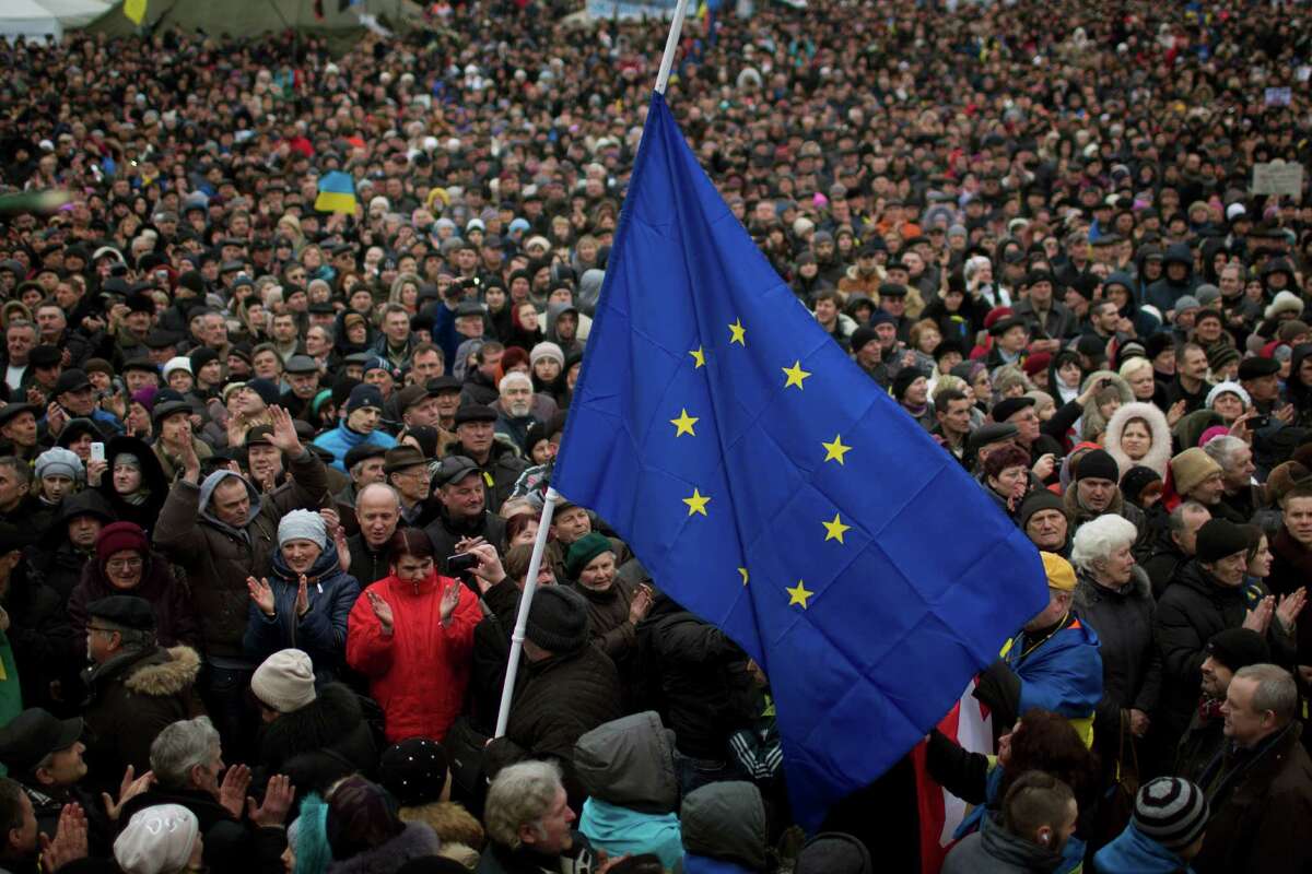 People applaud as the European Union flag held by a protester arrives at the Independence square during a rally in Kiev Ukraine, Sunday, March 2, 2014. Ukraine's new prime minister urged Russian President Vladimir Putin to pull back his military Sunday in the conflict between the two countries, warning that "we are on the brink of disaster." The comments from Arseniy Yatsenyuk came as a convoy of Russian troops rolled toward Simferopol, the capital of Ukraine's Crimea region, a day after Russian forces took over the strategic Black Sea peninsula without firing a shot. (AP Photo/Emilio Morenatti)