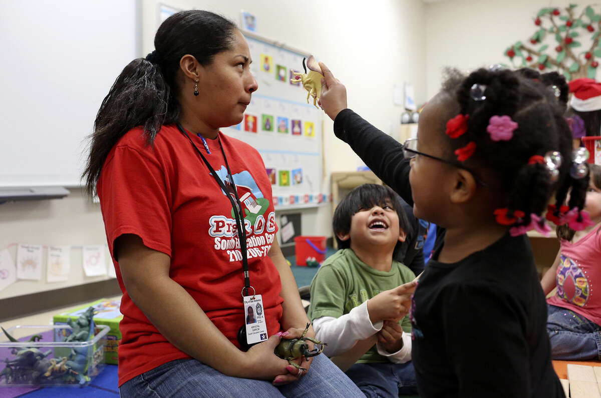 Pre-K teacher assistant Krystal Garcia pauses with Mya Johnson, 4 (right), and Victor Victela, 5, at the South Pre-K 4 SA Center in San Antonio. Officials hope the program will better prepare students for higher grades and beyond.