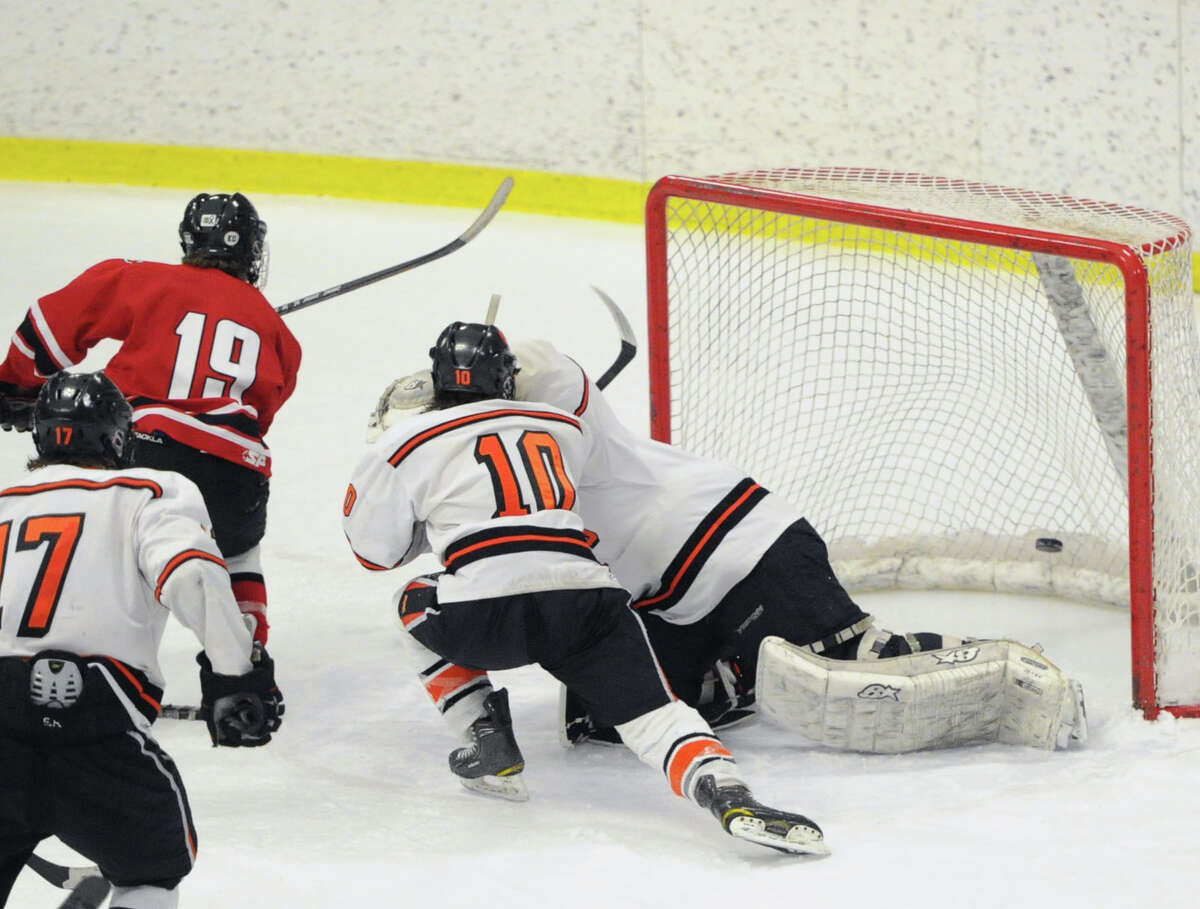 At left, Harry Stanton (#19) of New Canaan scores the winning goal in overtime getting the puck past Ridgefield goalie Patrick Sheehan-Delany as Ridgefield's Shane Luery (#10) defends as New Canaan defeated Ridgefield 3-2 during the FCIAC boys hockey semifinal between Ridgefield High School and New Canaan High School at Terry Conners Rink in Stamford, Conn., Wednesday, March 5, 2014.