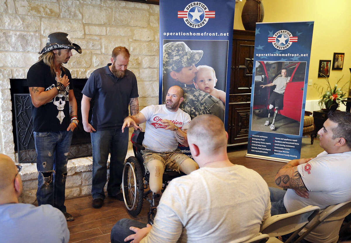 Musician Bret Michaels (from left) talks with U.S. Air Force and Air National Guard veteran Kenny Walker and U.S. Army veteran Stephen Jackel, both of whom were injured in Afghanistan, and other wounded warriors at Homefront Village.