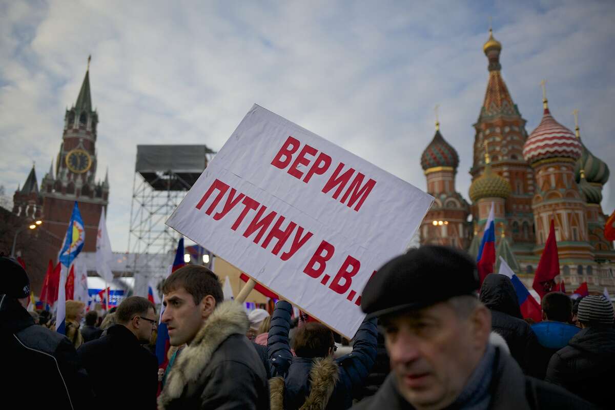 A Pro-Putin demonstrators holds posters reading "We Believe Putin!" as others gather towards to Red Square in Moscow, Russia, Friday, March 7, 2014, with Spassky Tower, left, and St. Basile Cathedral, right, are in the background. Russia rallied support Friday for a Crimean bid to secede from Ukraine, with a leader of Russia's parliament assuring her Crimean counterpart that the region would be welcomed as “an absolutely equal subject of the Russian Federation.” Across Red Square, 65,000 people waved Russian flags, chanting “Crimea is Russia!”(AP Photo/Alexander Zemlianichenko)
