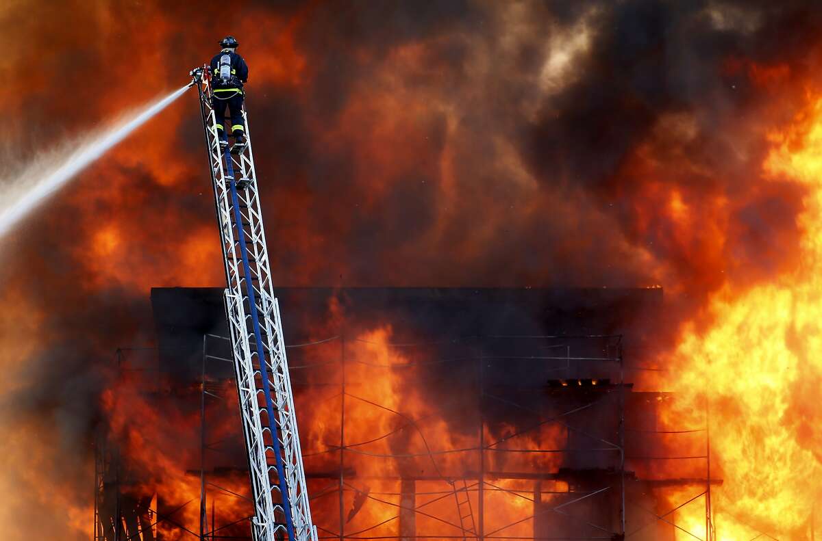 A San Francisco firefighter aboard an aerial ladder battles a five alarm fire at a fire in the Mission Bay area of San Francisco, Calif. on Tuesday March 11, 2014.