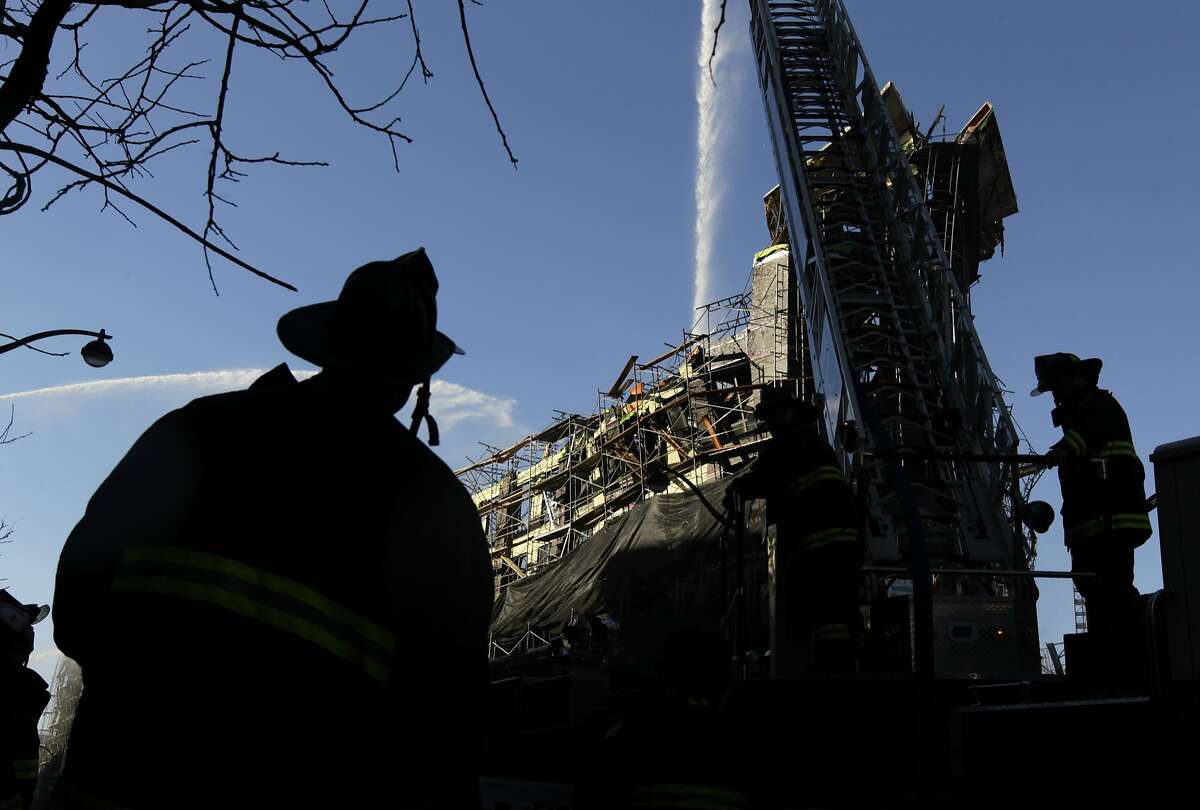 Firefighters continue to pour water on hotspots in San Francisco, Calif. on Wednesday, March 12, 2014, that continue to burn after Tuesday's huge five-alarm fire at a Mission Bay apartment building construction site.