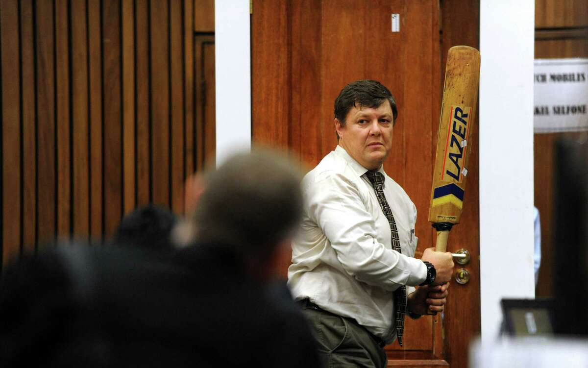 During Oscar Pistorius' trial, forensic investigator Johannes Vermeulen, cricket bat in hand, demonstrates how Pistorius' bathroom door could have been broken down with the bat.