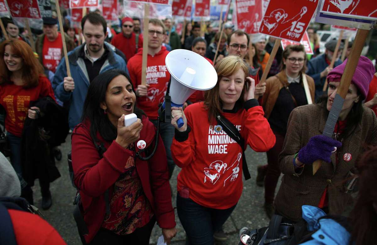 Seattle City Councilmember Kshama Sawant, left, leads a chant during a march in Seattle to raise the minimum wage.