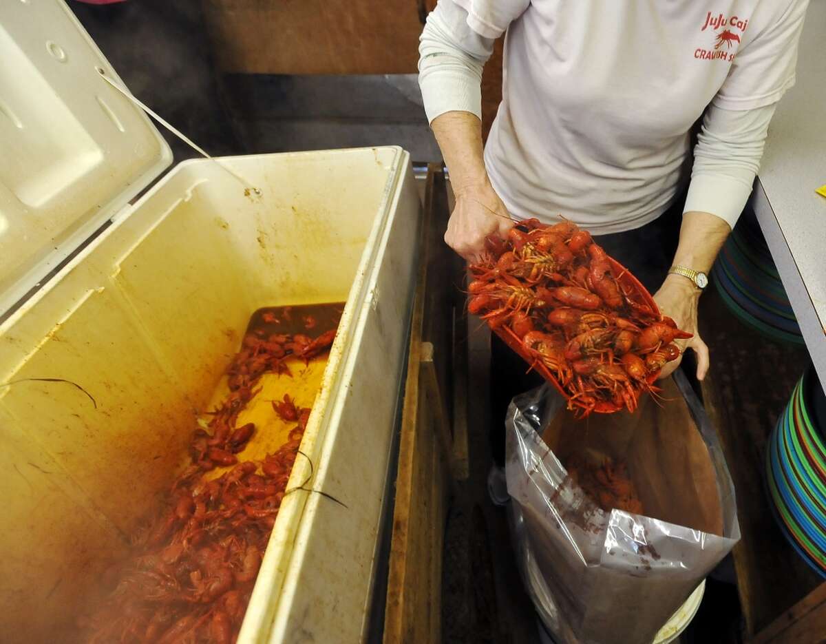Mary Ferguson scoops up crawfish from an insulated cooler for a to-go order Thursday. JuJu's Cajun Crawfish in Fannett serves up nothing but crawfish, corn on the cob, and potatoes during the mudbug season. The small, family-owned restaurant is in its 12th year. Photo taken Thursday, 2/27/14 Jake Daniels/@JakeD_in_SETX