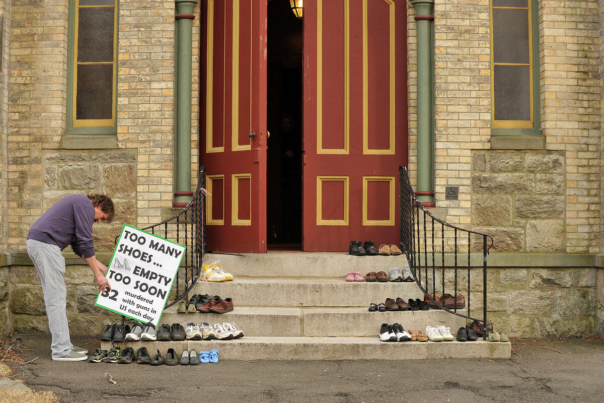 Norris Wakefield affixes a sign next to shoes on the steps of the Unitarian Universalist Society in Stamford, Conn., before the start of the Interfaith Council of Southwestern Connecticut's vigil to prevent gun violence as part of the nation-wide Gun Violence Prevention Sabbath weekend on Sunday, March 16, 2014. People were asked to leave a pair of shoes on the church steps in remembrance of the people that no longer occupy the shoes because of gun violence.