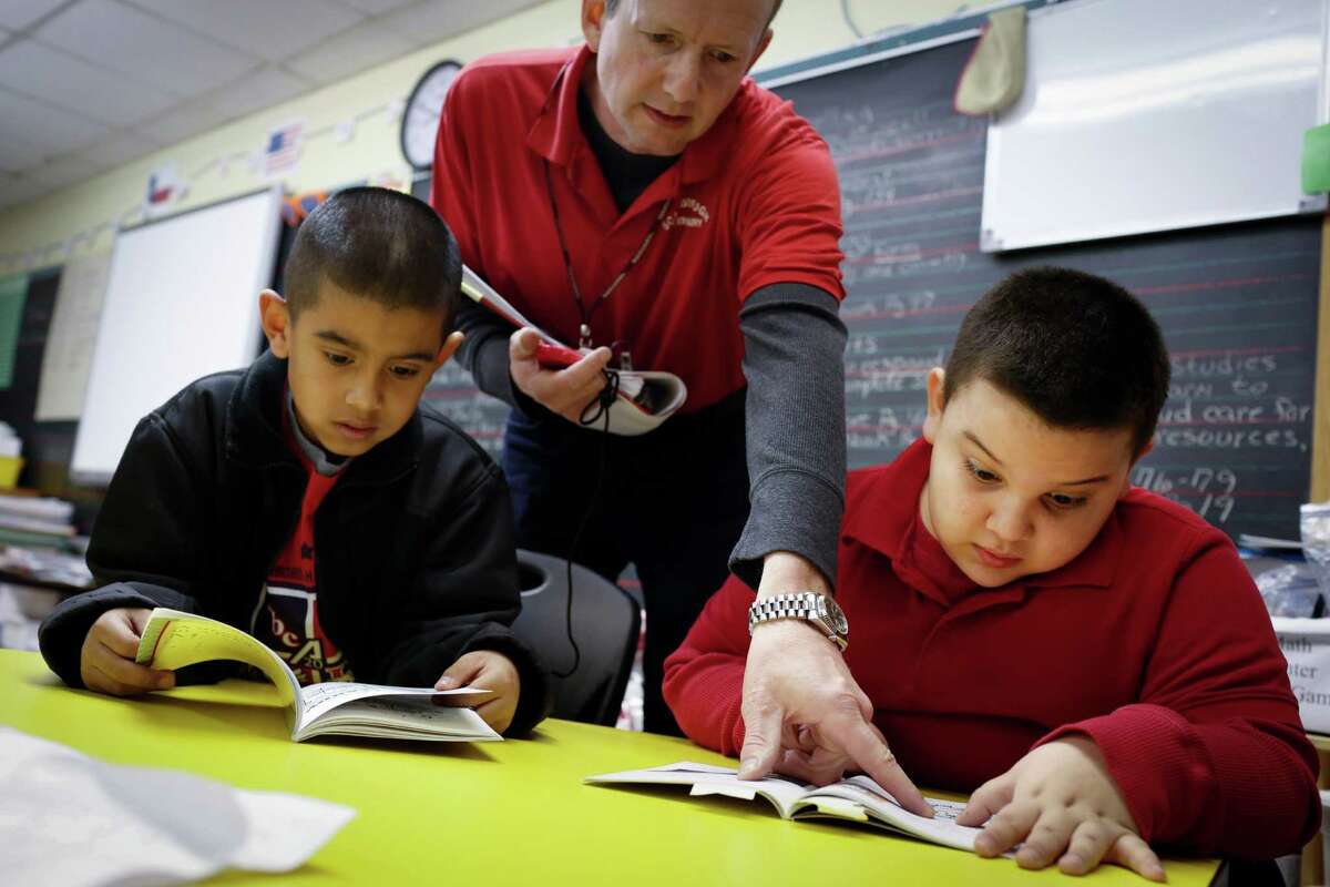 John Ureste, 7, right, practices reading with the help of second grade teacher Mark Cwenar Jan. 30, 2014 in Houston at Scarborough Elementary School. Carlos Soto, 7, is at left. (Eric Kayne/For the Chronicle)