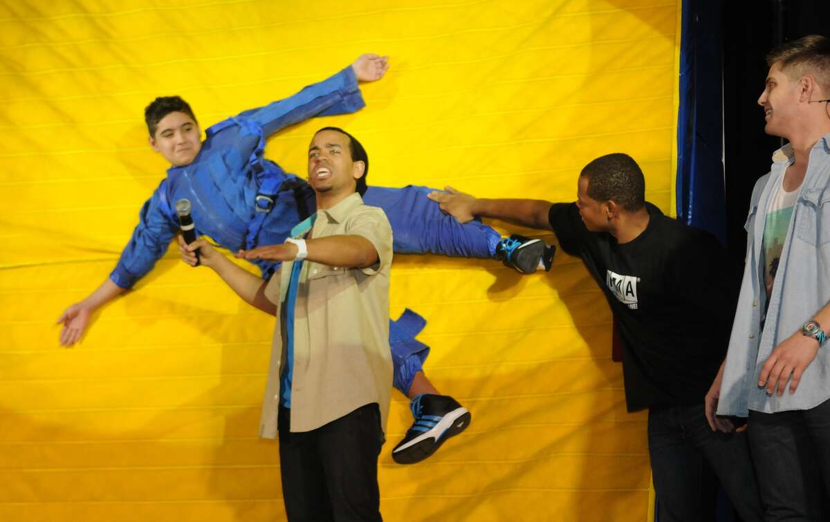 Kenneth Leal, 12, left, gets velcro-walled during a Newtonís Three Laws of Motion demonstration presented by John James, center, of Atlanta and the Forces in Motion Live cast at Wunderlich Intermediate School in Klein.