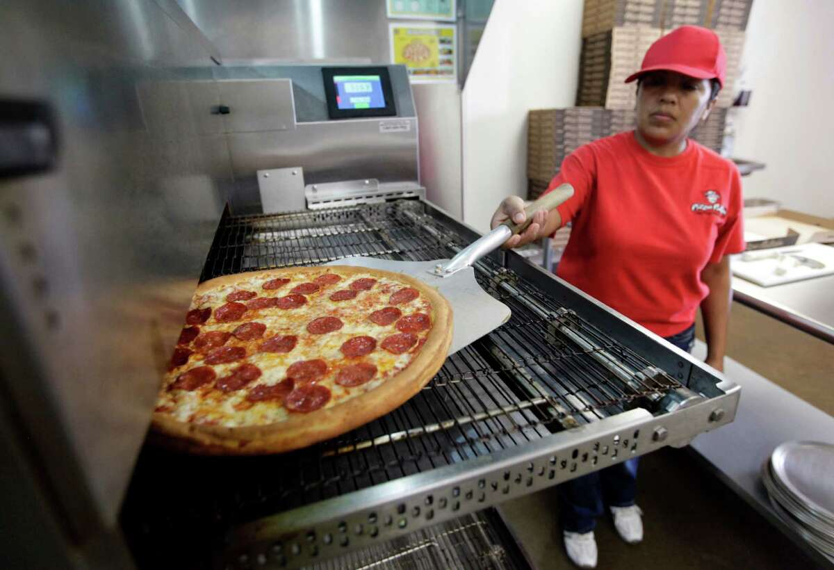 Employee Rosy Tirado pulls a pepperoni pizza from an oven at a Pizza Patron Dallas, Texas, Thursday, May 24, 2012. The fast food restaurant has drawn the attention of the Texas community for its advertising campaigns aimed at first-generation Mexican immigrants and Mexican-Americans. Five years ago Pizza Patron organized a controversial advertising campaign that allowed people to pay for their pizzas with Mexican pesos. The most recent promotion is scheduled for June 5 only, between 5-8 p.m., while supplies last, in which any customer who places their pizza order in Spanish will receive a free large pepperoni pizza. (AP Photo/Tony Gutierrez)