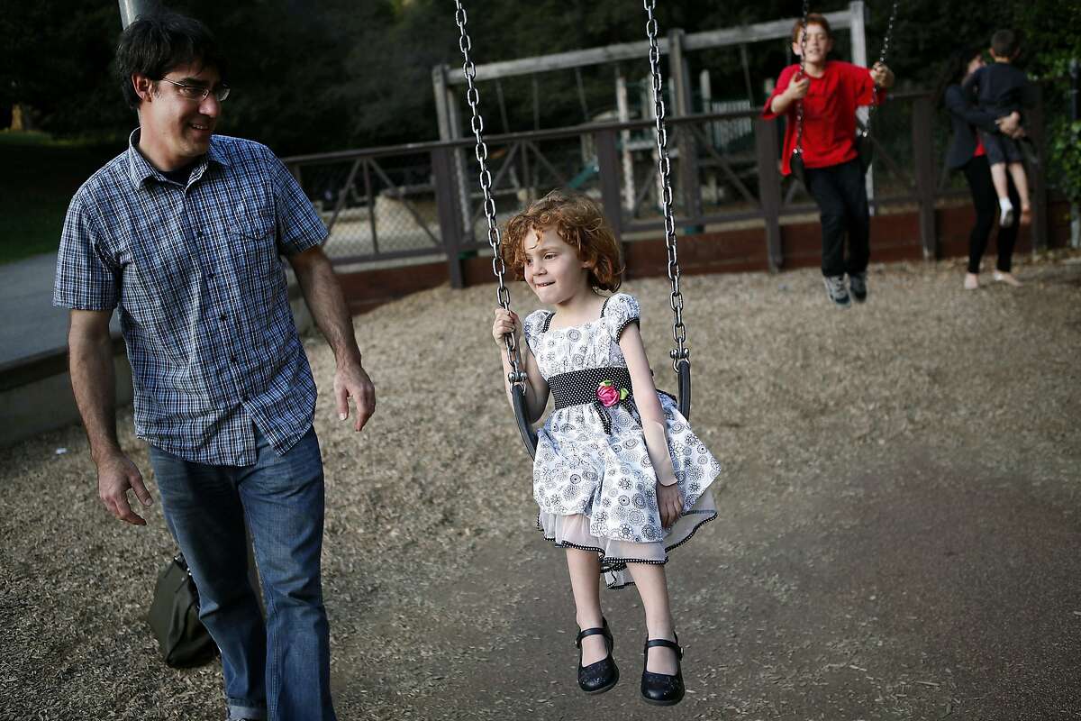 Sophia Jarvis,4, gets a push on the swings from her dad Jeff Jarvis as her big brother Jack Jarvis, 8, swings next to her at Condornices Park in Berkeley, CA, Wednesday, March 19, 2014. Sophia was struck in 2012 with the recent polio-like syndrome that has hit about two dozen kids in California, including five in the Bay Area.