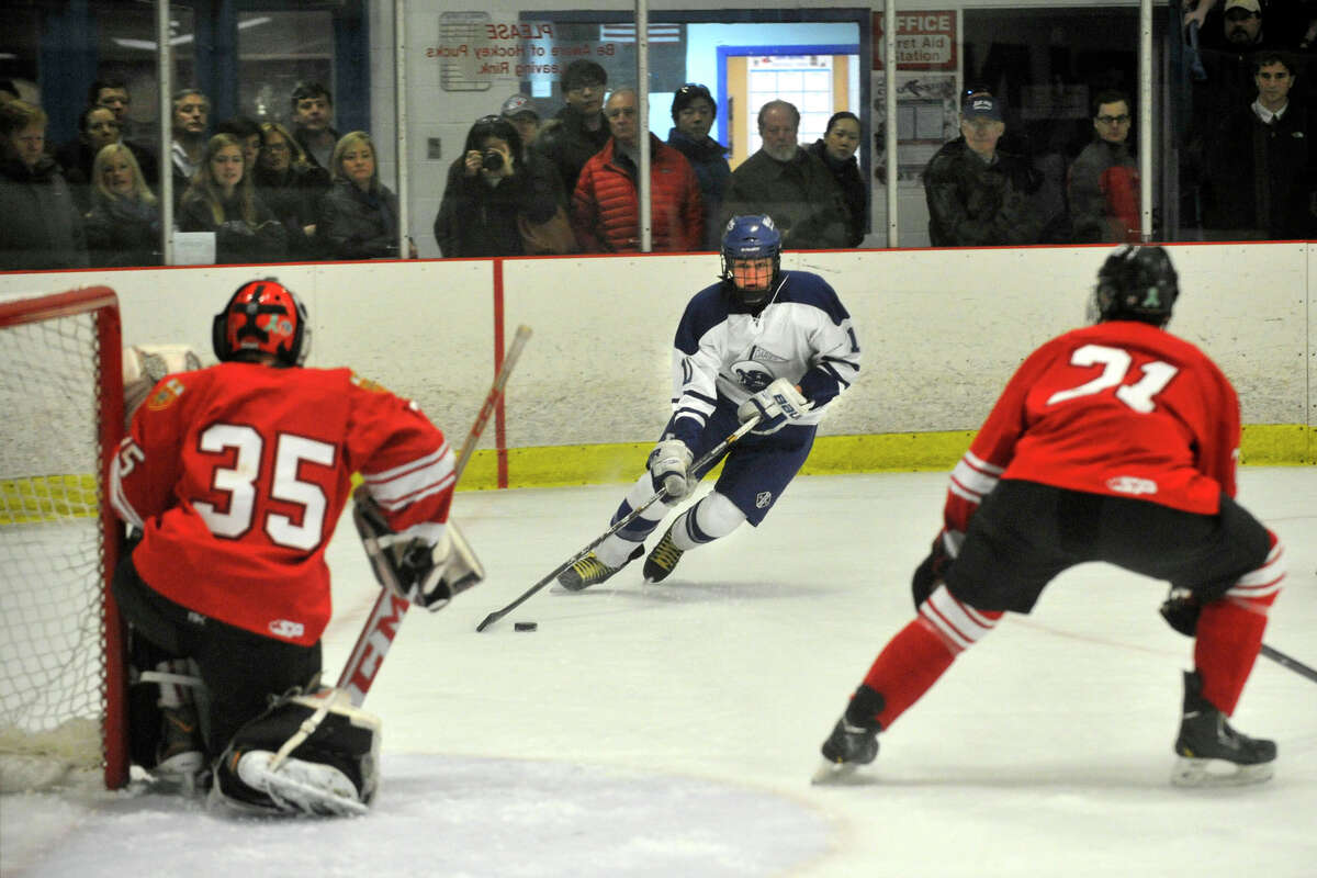 Darien's Nicholas Tuzinkiewicz eyes the Fairfield Prep goal that is guarded by goalie Christopher Gutierrez, left, and Bryan Connell during their hockey game at Darien Ice Rink in Darien, Conn., on Feb. 6, 2014. Darien won in overtime, 3-2.