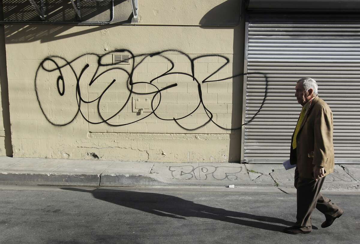 Property owner Larry Matthews walks past graffiti defacing his building on Erie Alley and South Van Ness Avenue in San Francisco, Calif. on Thursday, March 20, 2014. Matthews says he spends $15,000 annually to cover graffiti on the building and is not happy with the city's current graffiti eradication policy.