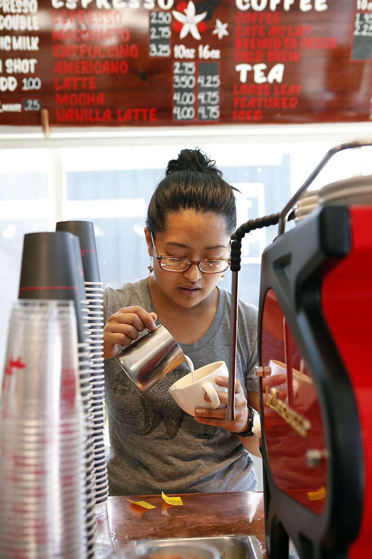 Barista Cat Mungcal pours designs into latte foam while working at Equator Coffees at Proof Lab Surf Shop in Mill Valley, CA, Tuesday, March 18, 2014.
