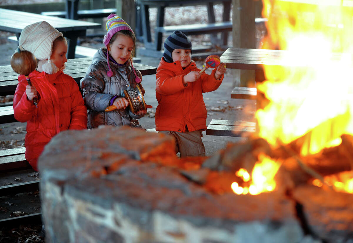 Ansonia Nature Center held a drum circle event by the fire to gently wake up Earth to celebrate the start of the vernal equinox in Ansonia, Conn. on Saturday March 22, 2014. Taking part in the circle from left to right is Zlata Tomashevskaia, 4, of New Haven, her sister Kseniia, 7, and family friend David Laganovski, 3, of Orange.
