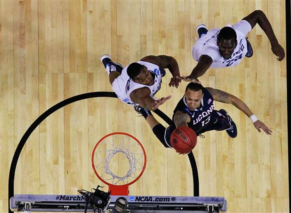 Connecticut's Shabazz Napier drives past Villanova's JayVaughn Pinkston, left, and Daniel Ochefu (23) during the first half of a third-round game in the NCAA men's college basketball tournament in Buffalo, N.Y., Saturday, March 22, 2014. (AP Photo/Bill Wippert)