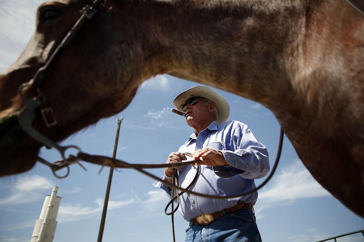 Jack Mitchell lights a cigar while talking with neighbors that came to help move some of his cattle from one pasture to another on his ranch in Alpaugh, CA, Thursday, March 20, 2014. Farmer Jack Mitchell has sold about 2000 acres of his ranch to the Atwell Island Sanctuary which, through the Bureau of Land Management, is turning former farm land in the San Joaquin Valley back to it's natural pre-agriculture state.