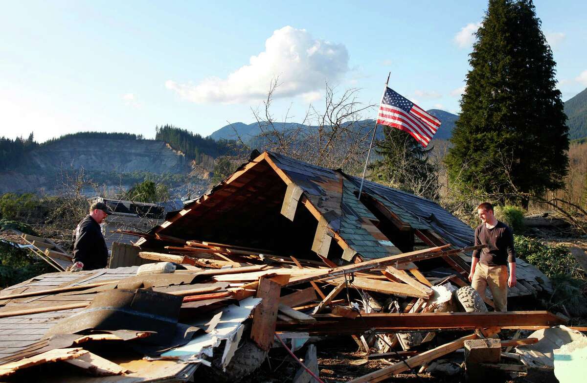 Brian Anderson, left, and Coby Young search through the wreckage of a home belonging to the Kuntz family Sunday, March 23, 2014, near Oso, Wash. The entire Kuntz family was at a baseball game Saturday morning when a fatal mudslide swept through the area. The family returned Sunday to search through what remained.