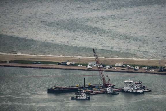 Emergency crews work along a barge that spilled oil after it was struck by a ship near the Texas City Dike on Sunday, March 23, 2014, in Texas City. Dozens of ships are in evolved in clean-up efforts to remove up to 168,000 gallons of oil that make have spilled into Galveston Bay after a ship and barge collided near the Texas City dike on Saturday afternoon.