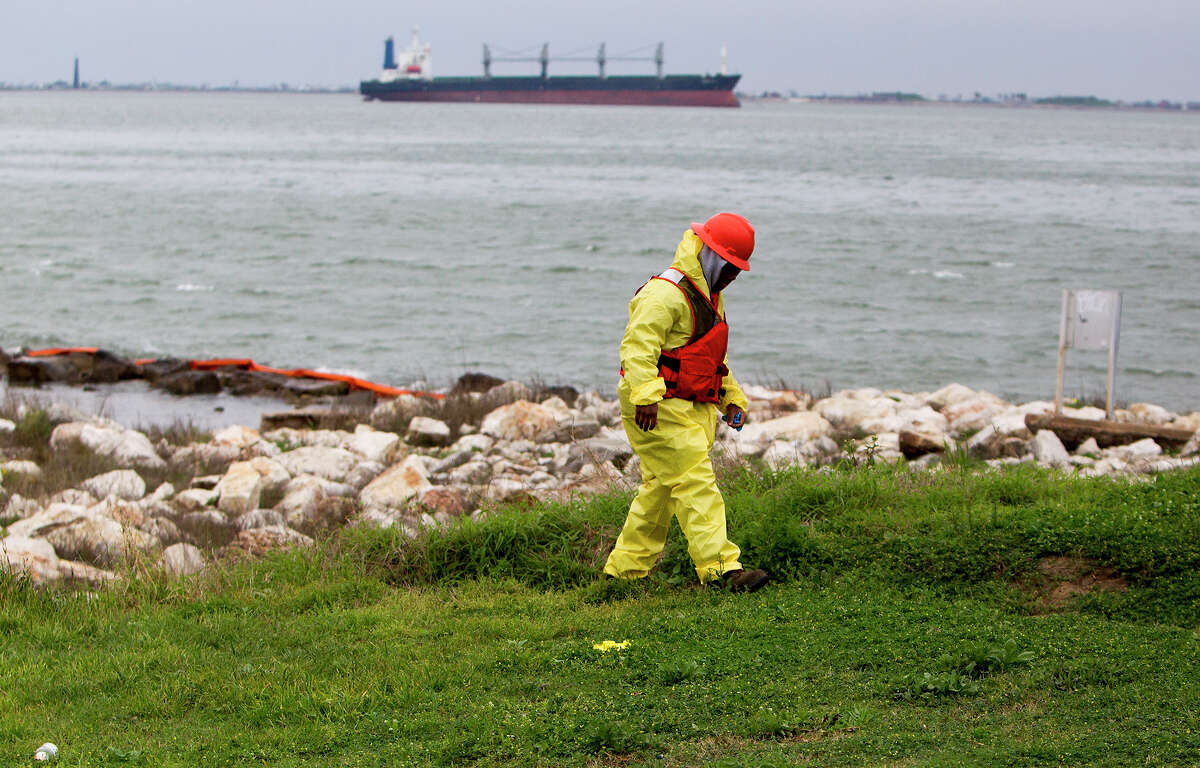 Crews work to clean oil from the shore area along Boddeker Rd. on the Eastern end of Galveston, Monday, March 24, 2014, in Galveston. The oil washed ashore after a barge carrying heavy oil collided with a ship Saturday in the busy Houston Ship Channel.