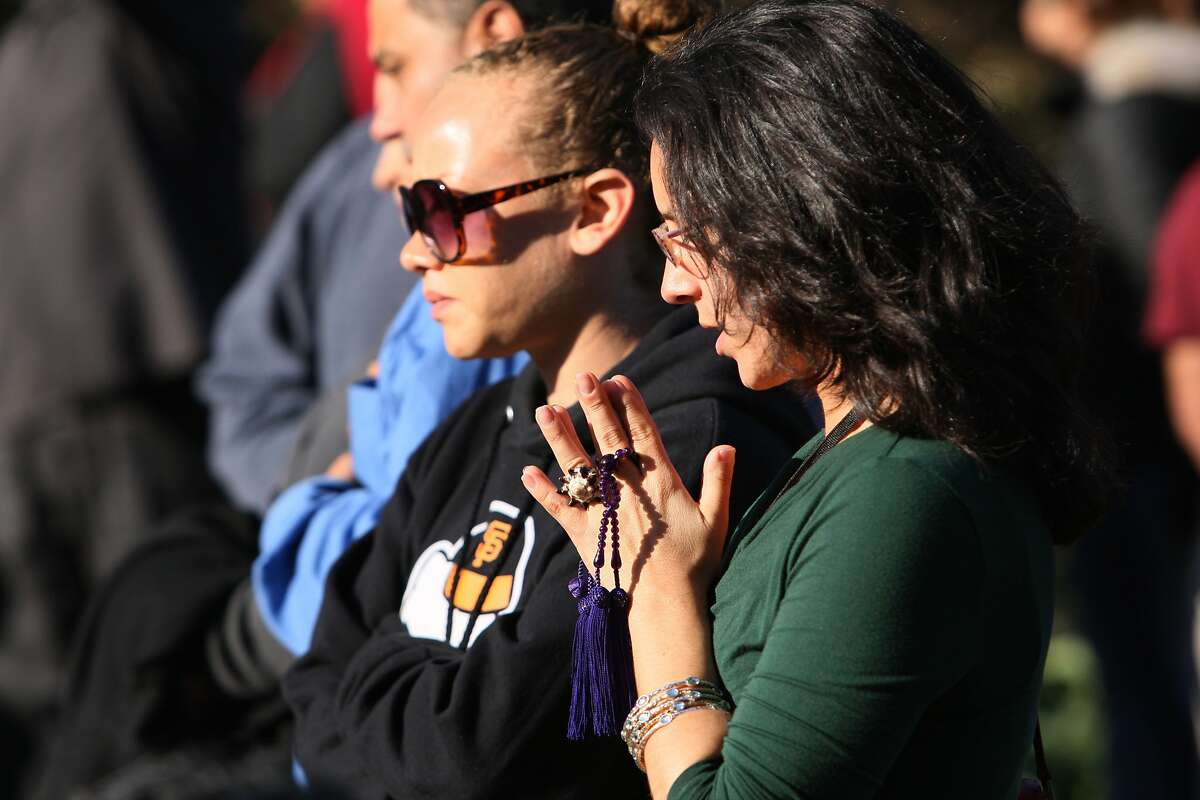 A woman clasps her hands together in mourning at a vigil held for Alejandro Nieto, a man fatally shot by police last Friday evening in Bernal Heights Park, in San Francisco, Calif. on March 24, 2014.