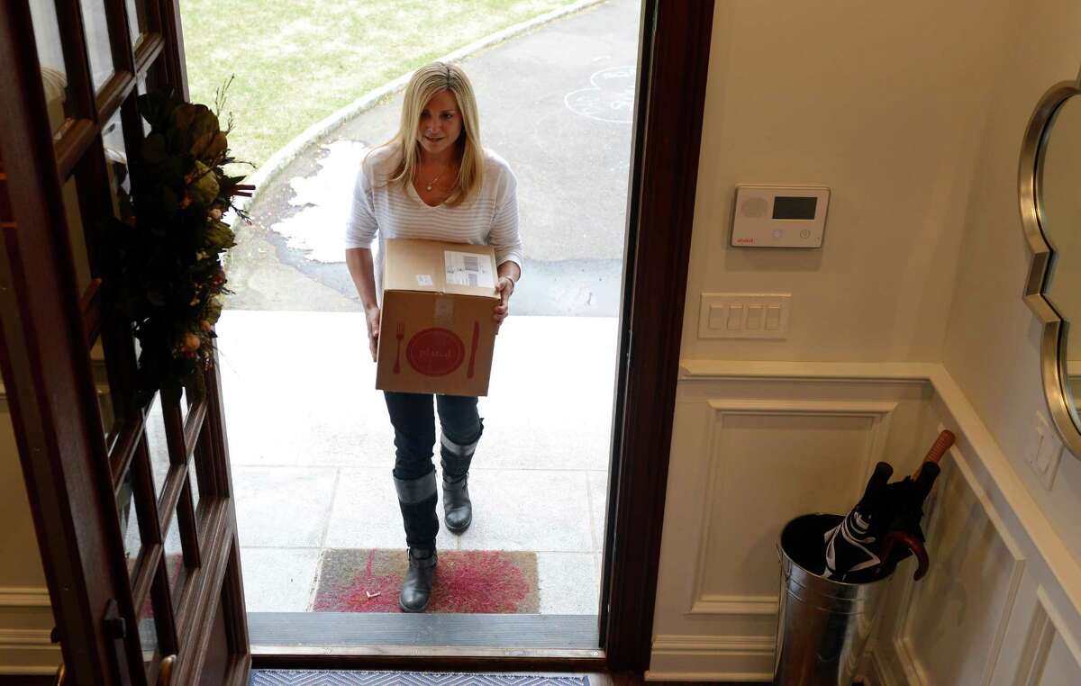 Mimi Shalhoub carries in her ready-to-cook dinner kits from Plated.com Tuesday, Mar. 25, 2014, at her home in Fairfield, Conn. The box, delivered right to her door, contains everything needed to prepare a gourmet meal.