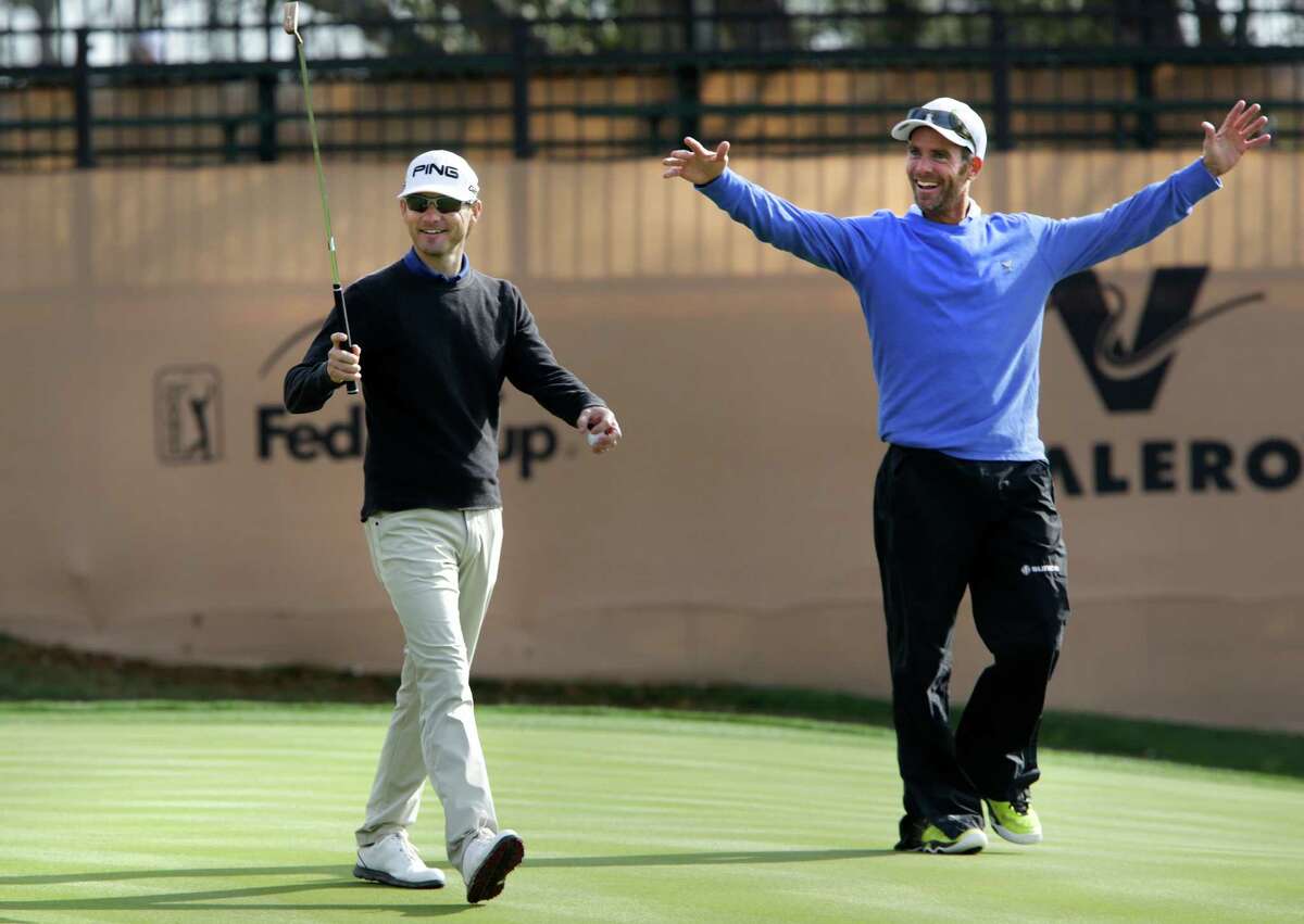 Heath Slocum, left, and his caddie wave to fans as they walk off the 18th green after a practice round preparing for the 2014 Valero Texas Open on the TPC San Antonio AT&T Oaks Course. Tuesday, March 25, 2014.