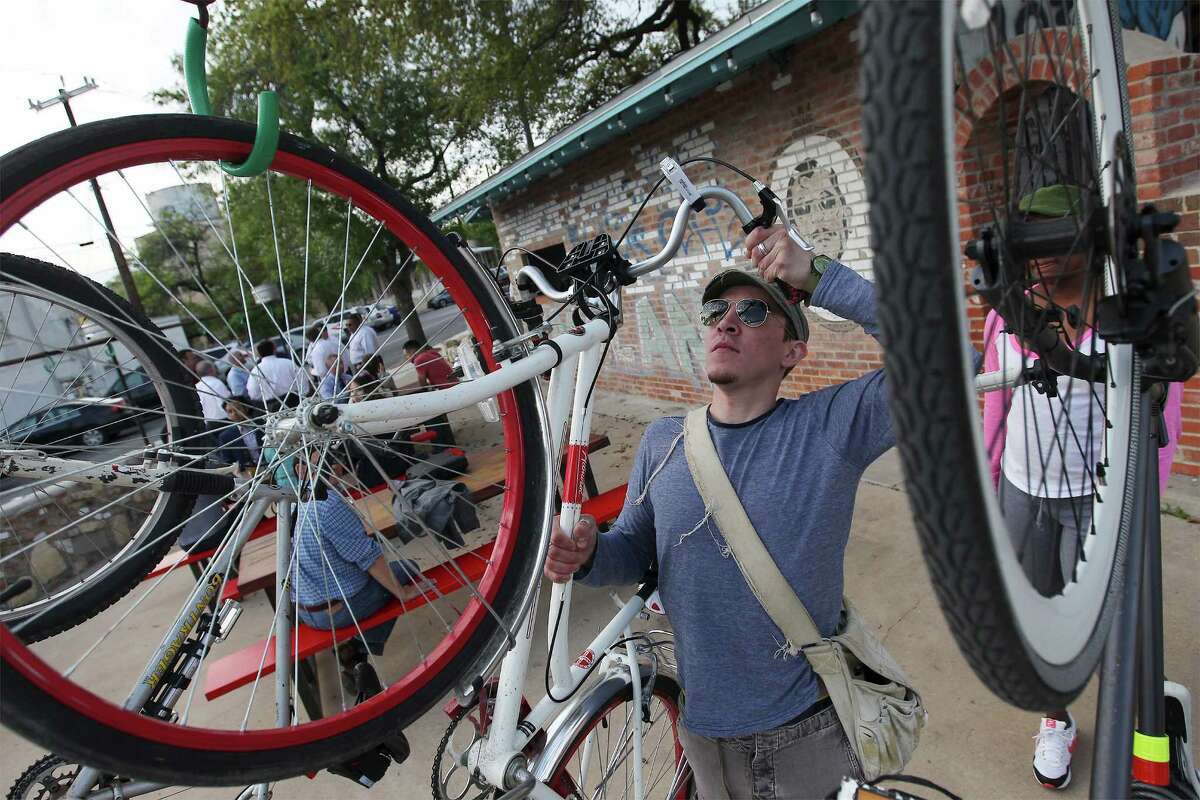 Patron Nicholas Kenna hangs a friend's bike at the entrance of the new TacoLand.