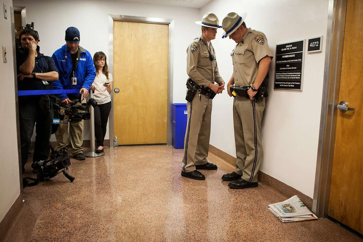 California Highway Patrol Officers stand guard outside state Senator Leland Yee's office at the State Capitol in Sacramento, California as FBI agents search for evidence inside on March 26, 2014.