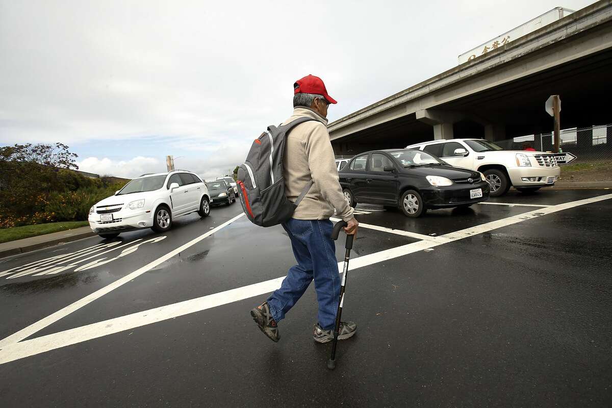 Irineo Camacho, an employee at Golden Gate Fields, crosses the street at the Gilman Street offramp from I-80 in Berkeley, Calif., on Tuesday, March 25, 2014. The intersection of Gilman Street and Interstate 80 in West Berkeley is a nightmare for drivers, pedestrians, and cyclists, as roughly twelve different off-ramps, streets and frontage roads all converge into one mass of confusion. A lack of lights, poor lane markings and signage might be fixed as the city debates whether to put in traffic circles for some help.