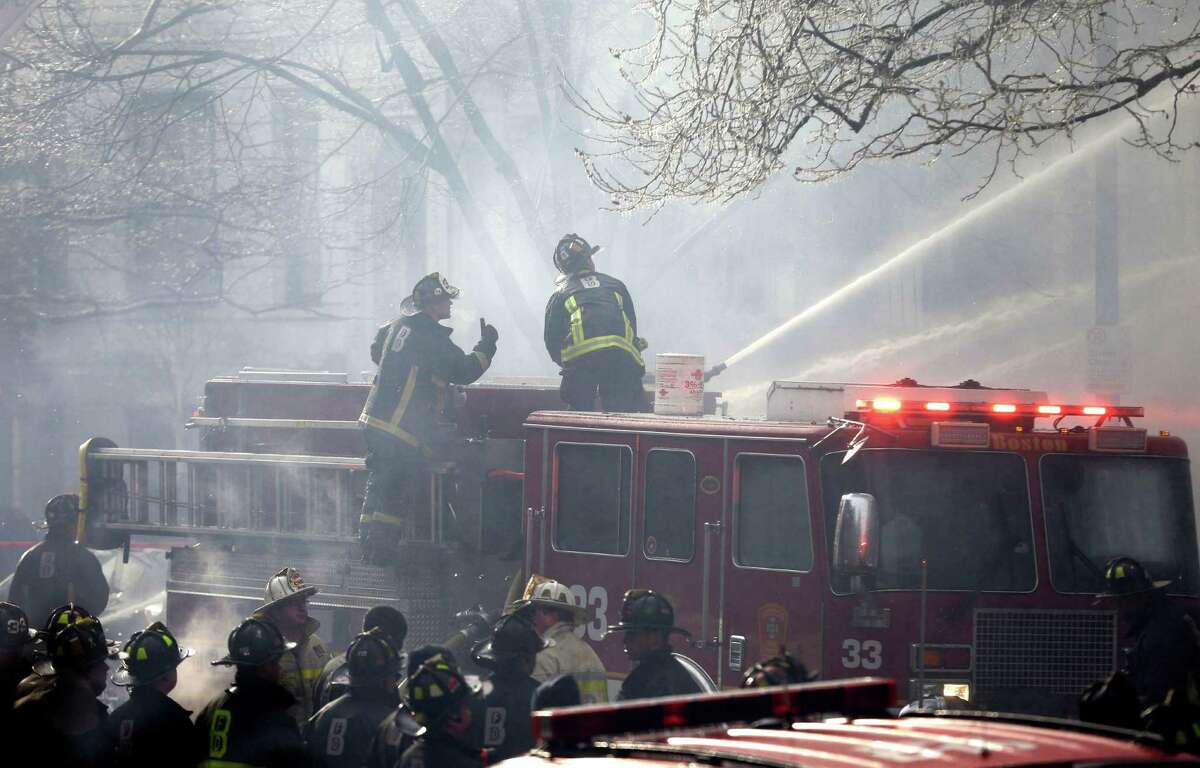 ADDS LAST SENTENCE - Fighters battle a multi-alarm fire at a four-story brownstone in the Back Bay neighborhood near the Charles River, Wednesday, March 26, 2014, in Boston. A Boston city councilor said two firefighters have died in a fire that ripped through a brownstone. (AP Photo/Steven Senne)