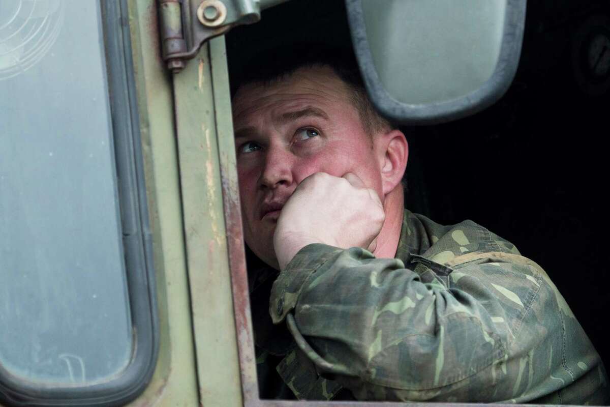 A Ukrainian soldier looks in the rear-view mirror as Ukrainian tanks are transported from their base in Perevalnoe, outside Simferopol, Crimea, Wednesday, March 26, 2014. Ukraine has started withdrawing its troops and weapons from Crimea, now controlled by Russia. (AP Photo/Pavel Golovkin)