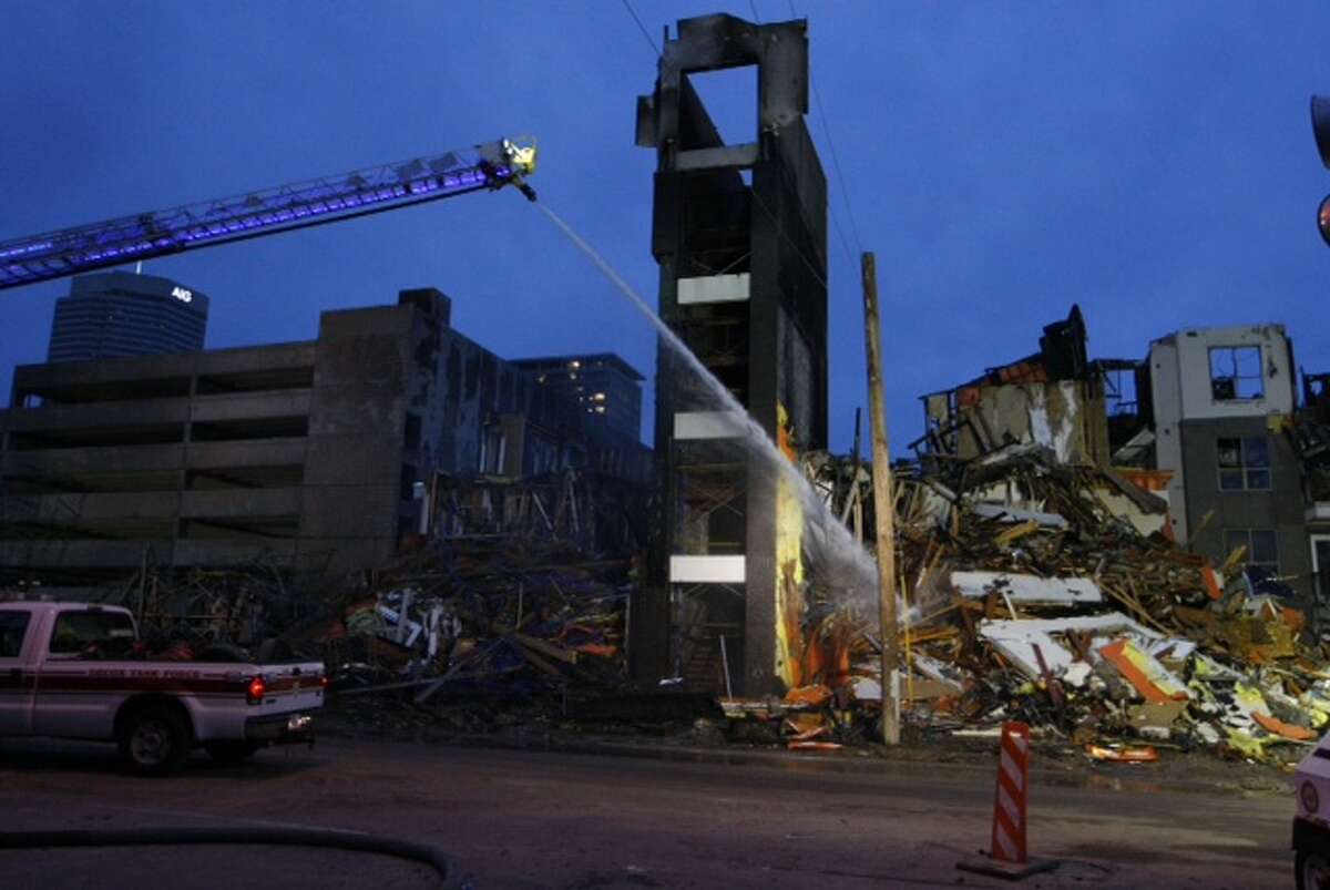 Houston firefighters continued to douse hot spots Wednesday morning, the day after a five-alarm inferno consumed an apartment complex under construction near downtown.