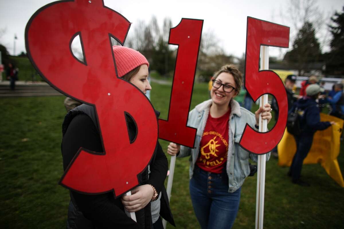 Kate Garrow and Justine Winnie hold signs during a march in Seattle to raise the minimum wage to $15 per hour. Hundreds of people marched from Judkins Park to Seattle Central Community College where a rally was held. Photographed on Saturday, March, 15, 2014. (Joshua Trujillo, seattlepi.com)