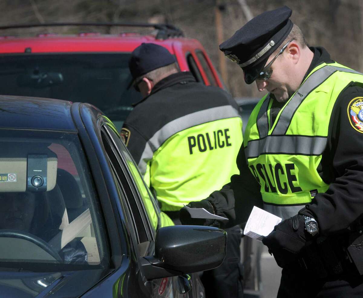 Bethel, Conn. Police Officer William May checks the paper work of a driver that is stopped for a possible cellphone violation. Police from area departments combined forces Thursday for the third wave of the "Phone in One Hand, Ticket in the Other" campaign. Police set up along Route 7 near the Ridgefield/ Redding border to stop drivers violating the cellphone law, Thursday, March 27, 2014.