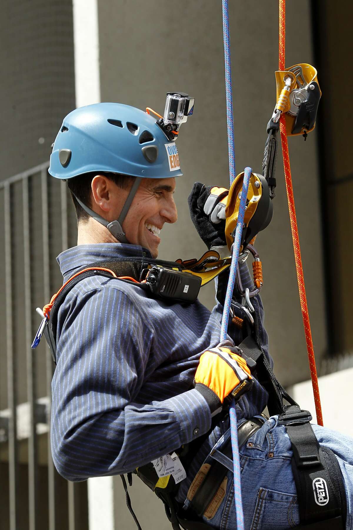 State Senator Mark Leno smiled as he finished the last few feet to the ground Thursday March 27, 2014 in San Francisco, Calif. Dozens of people will rappel free-hanging 230 feet from the roof of the Hyatt Regency to benefit Outward Bound and expand outdoor learning opportunities for low income students throughout the state.
