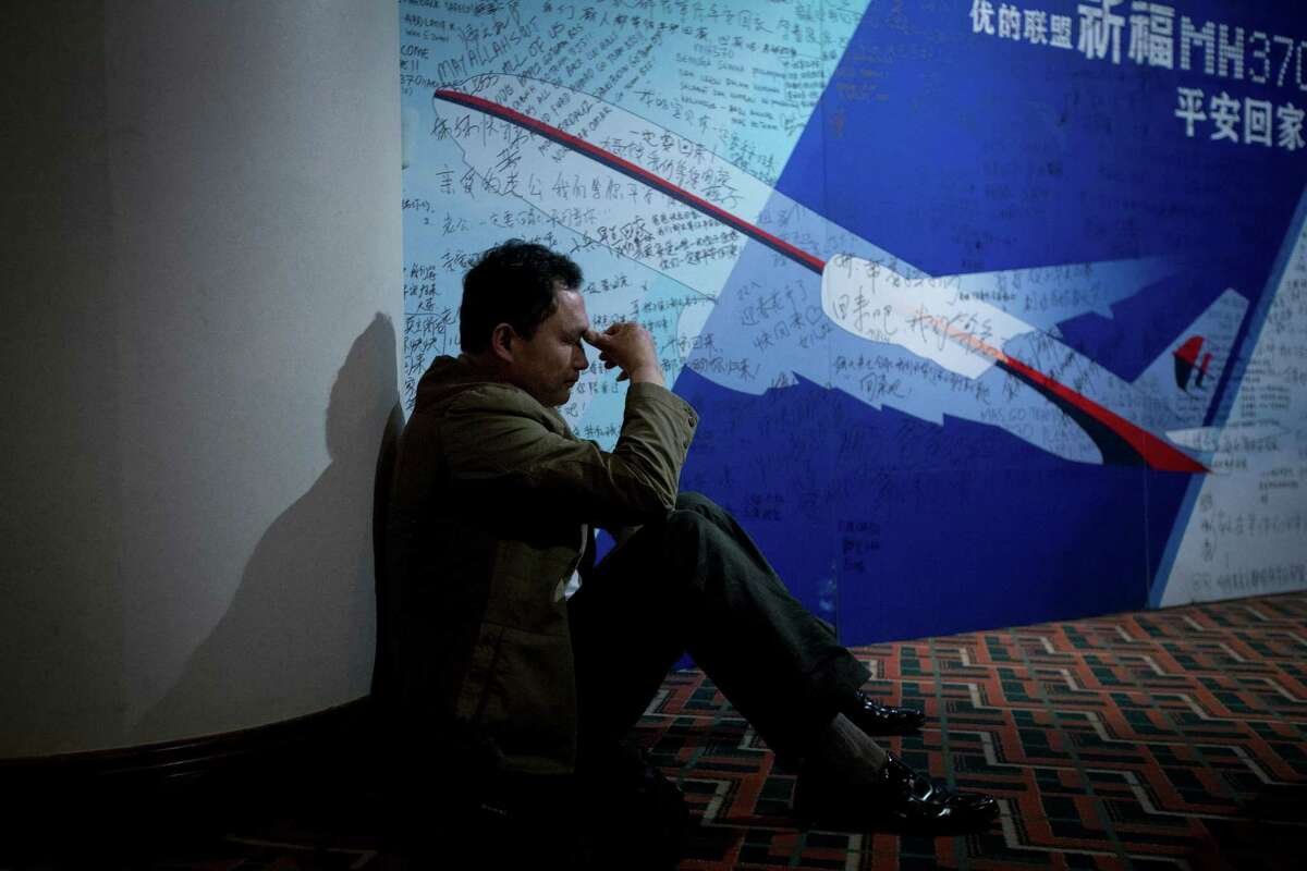 A man, one of the relatives of Chinese passengers onboard Malaysia Airlines Flight 370, rests near a board covered with written wishes at a hotel in Beijing, China, Saturday, March 29, 2014. Some of the wishes are "Dear husband, you must stay strong, I am waiting for you. Dear father, please be back home safely and the whole family is here waiting for you." (AP Photo/Alexander F. Yuan)