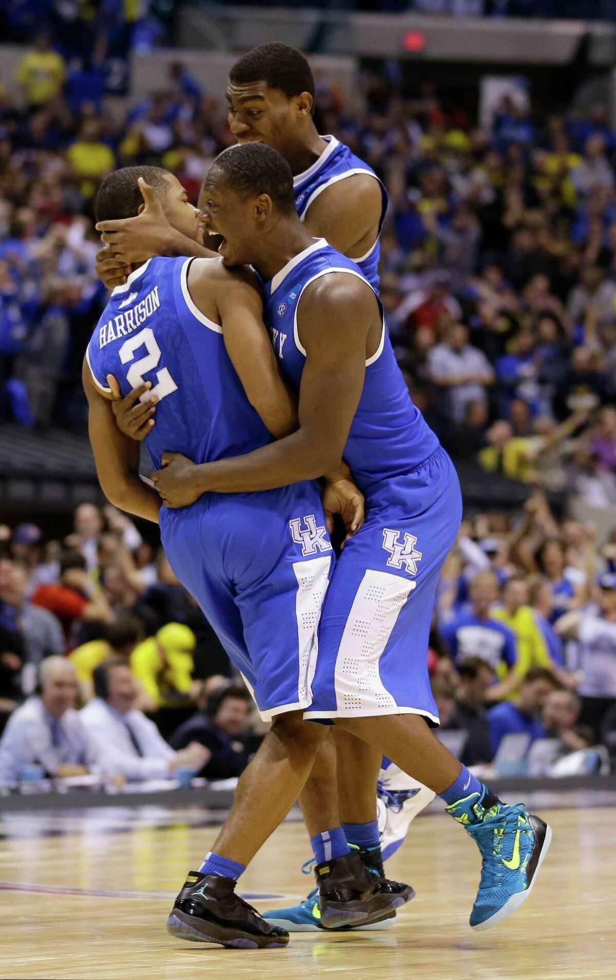 Aaron Harrison, left, keeps his cool, but teammates Julius Randle, top, and Dakari Johnson can't contain themselves after Harrison's game-winning 3-pointer with 2.3 seconds remaining Sunday.