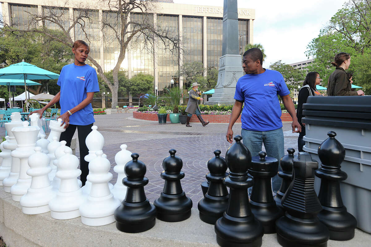 Southwest Airllines employees Loretta Bailey, left, and Wildor Saint Fort help set up an oversized chess game for the City of San Antonio reopening of Travis Park ceremony, Monday, March 31, 2014.