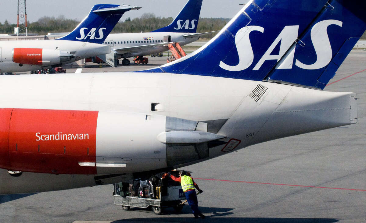 An SAS handler pushes a baggage wagon under one of SAS MD-80 series jets at Arlanda airport in Stockholm, on April 29, 2008. The Scandinavian Airline Group on Tuesday posted a first-quarter net loss of 1.13 billion kronor (121.2 million euros, 188 million dollars), up sharply from 47 million kronor a year earlier. AFP Photo / Johan Nilsson / SCANPIX ** SWEDEN OUT ** (Photo credit should read JOHAN NILSSON/AFP/Getty Images)