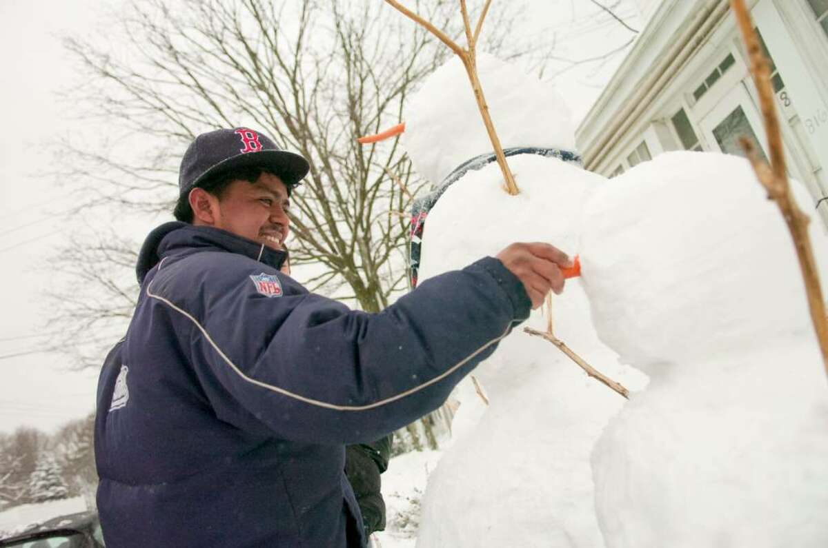 Nulfo De La Cruz puts the finishing touches on a snowman during a snowstorm in Stamford, Conn. on Tuesday, Feb. 10, 2010.