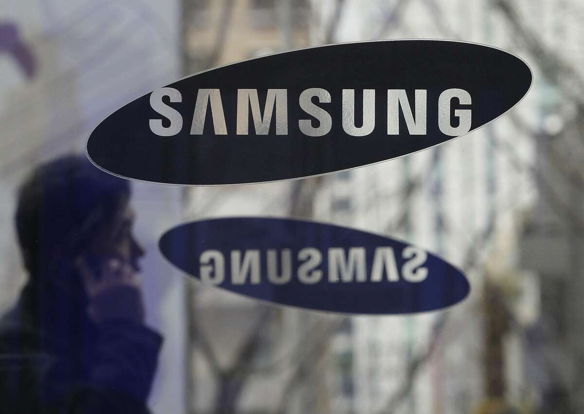 File - In this Dec. 12, 2013 file photo, a man passes by the Samsung Electronics Co. logos at its headquarters in Seoul, South Korea. Opening statements are underway in the latest patent fight over mobile devices between Apple and Samsung, the world's largest cellphone manufacturers. An Apple lawyer told jurors in San Jose, Calif., on Tuesday April 1, 2014, that Samsung quickly recognized that the iPhone was going to be a big seller when it first went on the market, and the South Korean company didn't have a product that could compete. (AP Photo/Ahn Young-joon, File)