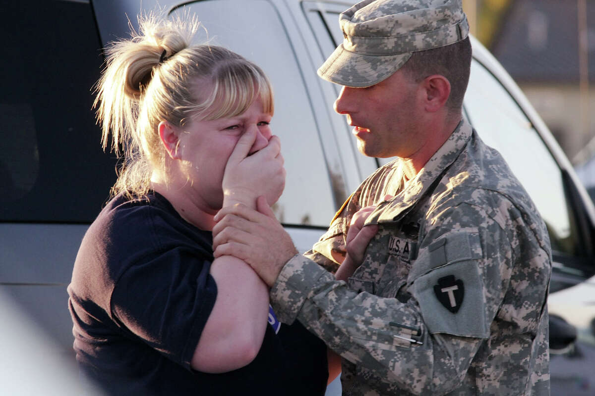 FILE - Sgt. Anthony Sills, right, comforts his wife as they wait outside the Fort Hood Army Base near Killeen, Texas on Thursday, Nov. 5, 2009. The Sills' 3-year old son is still in daycare on the base, which is in lock-down following a mass shooting earlier in the day. (AP Photo/Jack Plunkett)