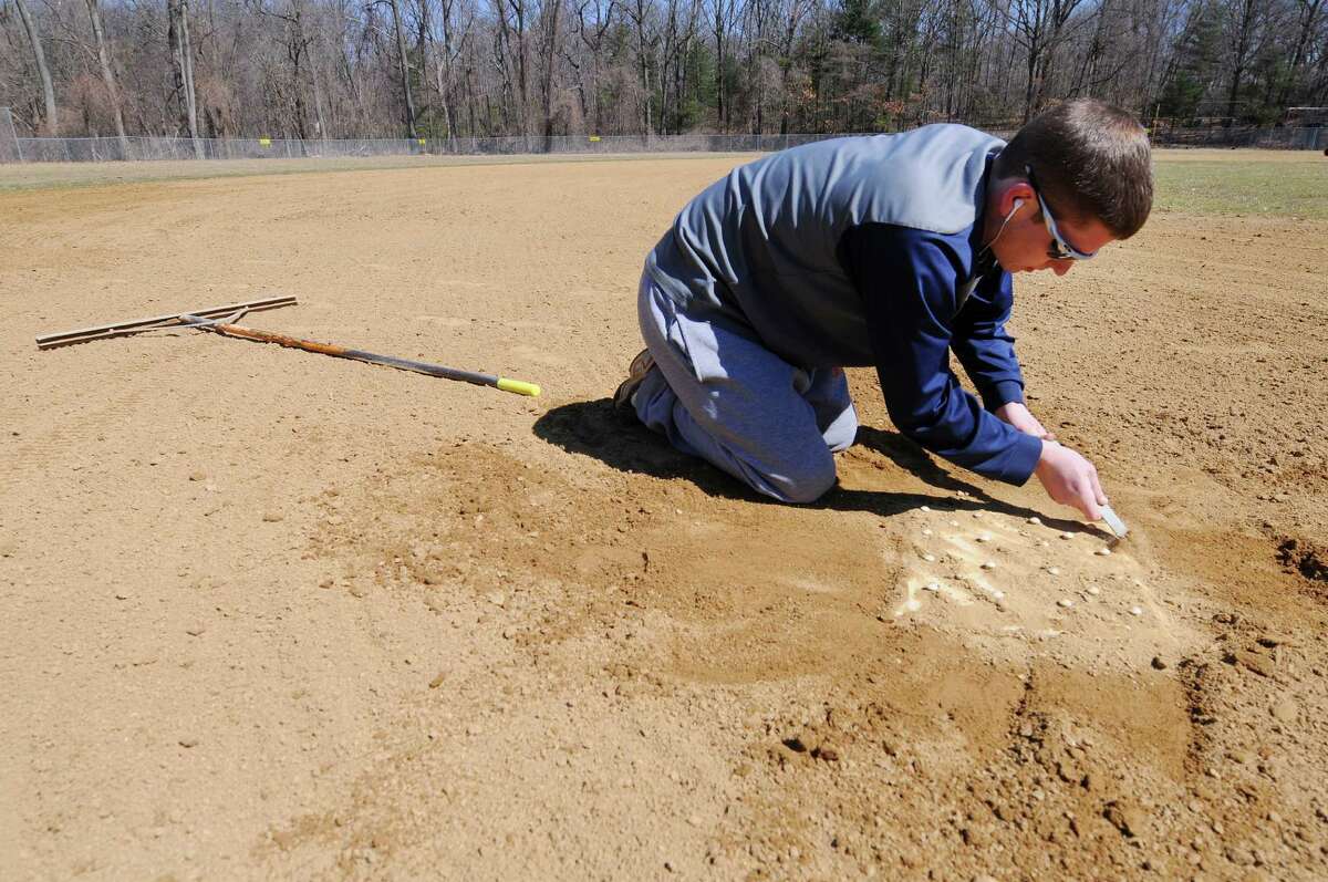 Tim Capitummino, vice president of the Schenectady Babe Ruth League, clears dirt from around third base at the Golf Rd. field in Central Park Thursday, April 3, 2014, in Schenectady, N.Y. Along with the Babe Ruth League, the Schenectady High School varsity and junior varsity teams practice on this field. (Paul Buckowski / Times Union)