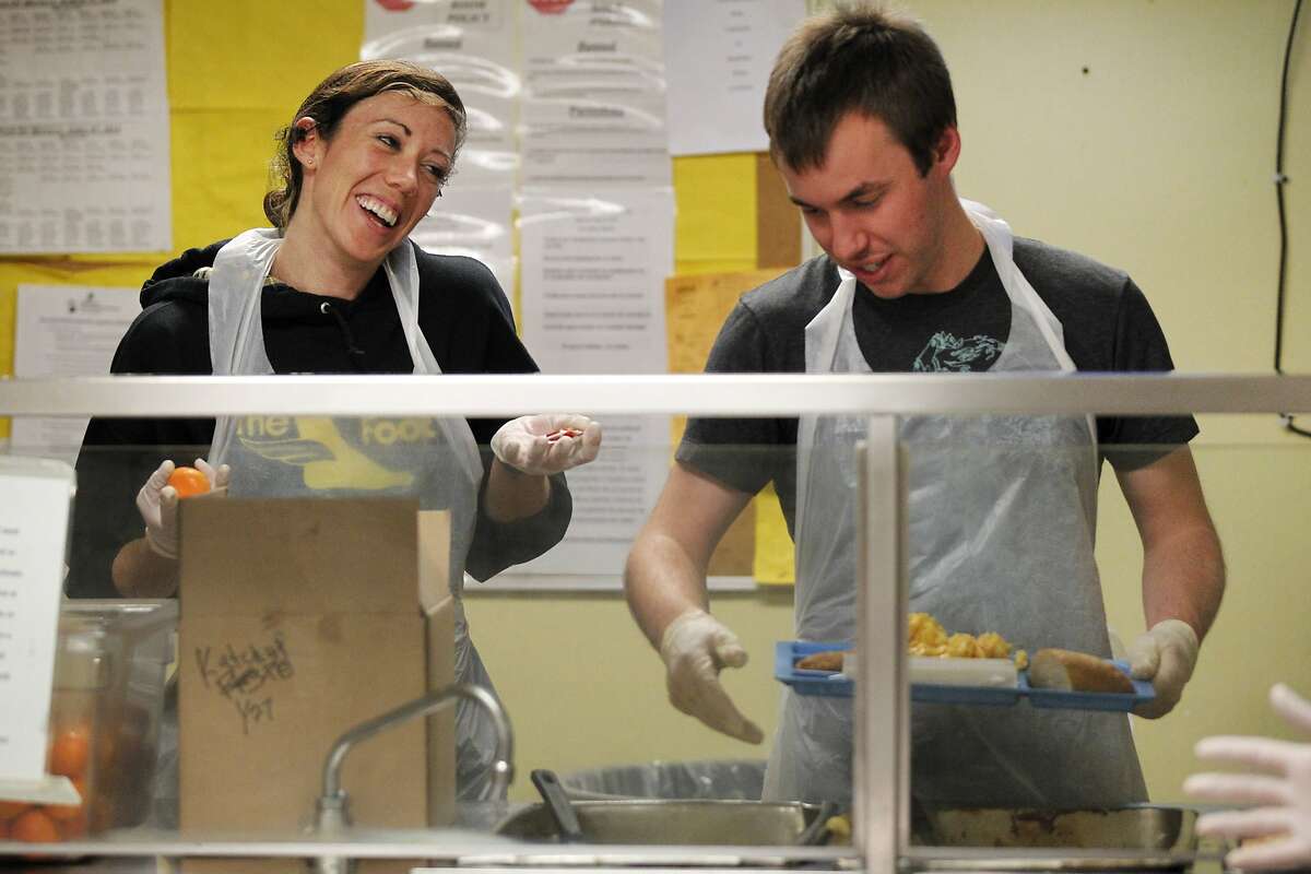 From left, Google employee volunteers Colleen Ryan, 25, and Morgan Conbere, 27, joke as they serve food to clients at dinnertime April 2, 2014 at Episcopal Community Services' Next Door shelter in San Francisco, Calif. The Google volunteers starting coming to the shelter to volunteer once a month, then as demand grew for the opportunity, another group was added. Now two groups of volunteers from Google come once a month each to Next Door.
