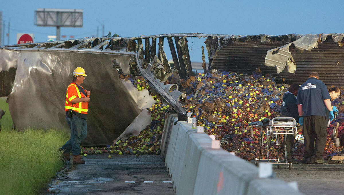 Authorities work the scene of a fatal 18-wheeler wreck inbound Highway 290 near Barker Cypress, Tuesday, April 8, 2014, in Houston. The driver of the truck transporting apples was killed after a fire, and a passenger was ejected. Hazmat was called after the truck also spilled 250 gallons of diesel onto the highway.