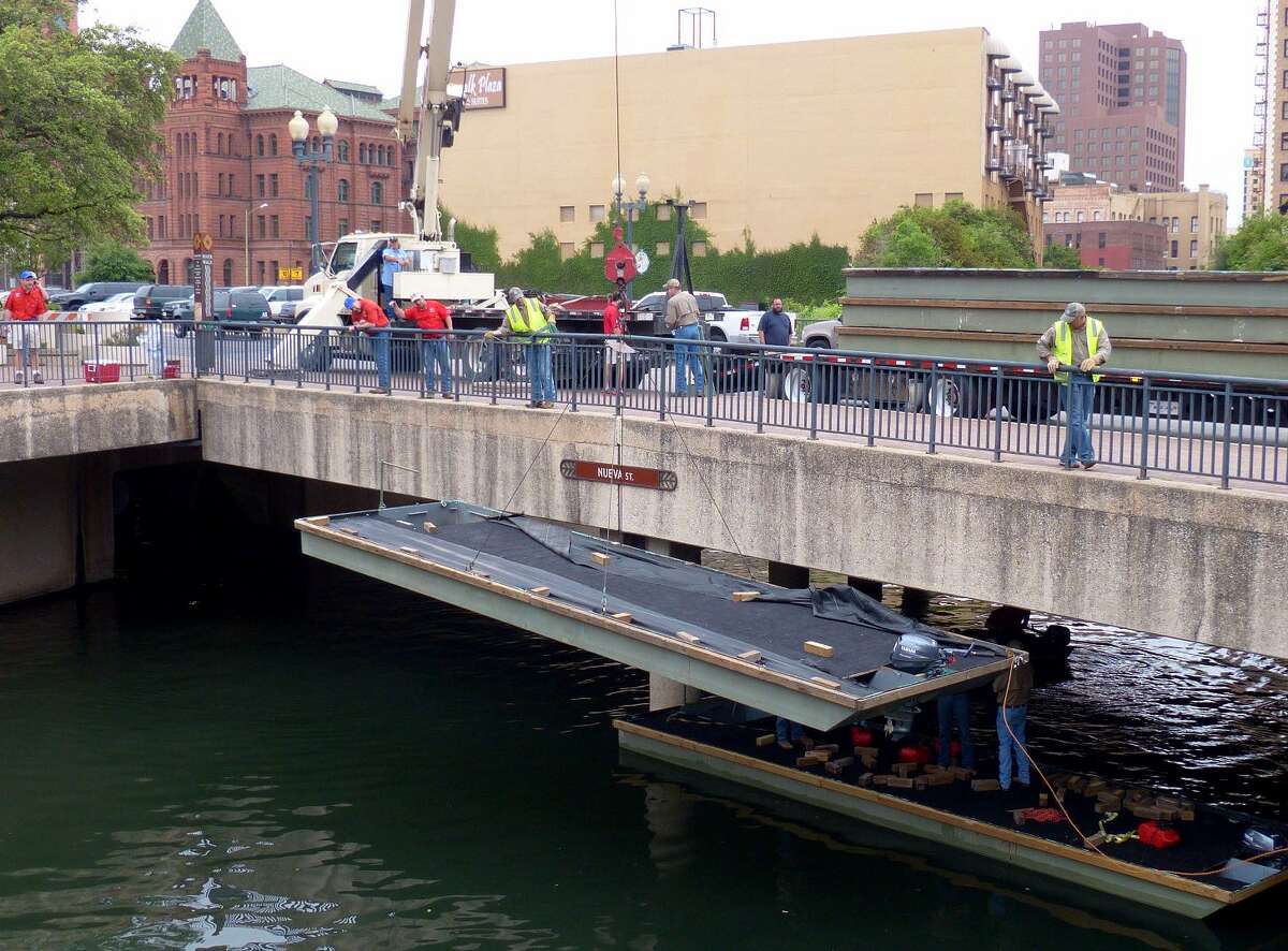 Workers lower a barge into the San Antonio River on Friday, April 11, 2014, during the annual "Barge-In Day," when barges to be decorated for the upcoming Fiesta Texas Cavaliers River Parade arrive.