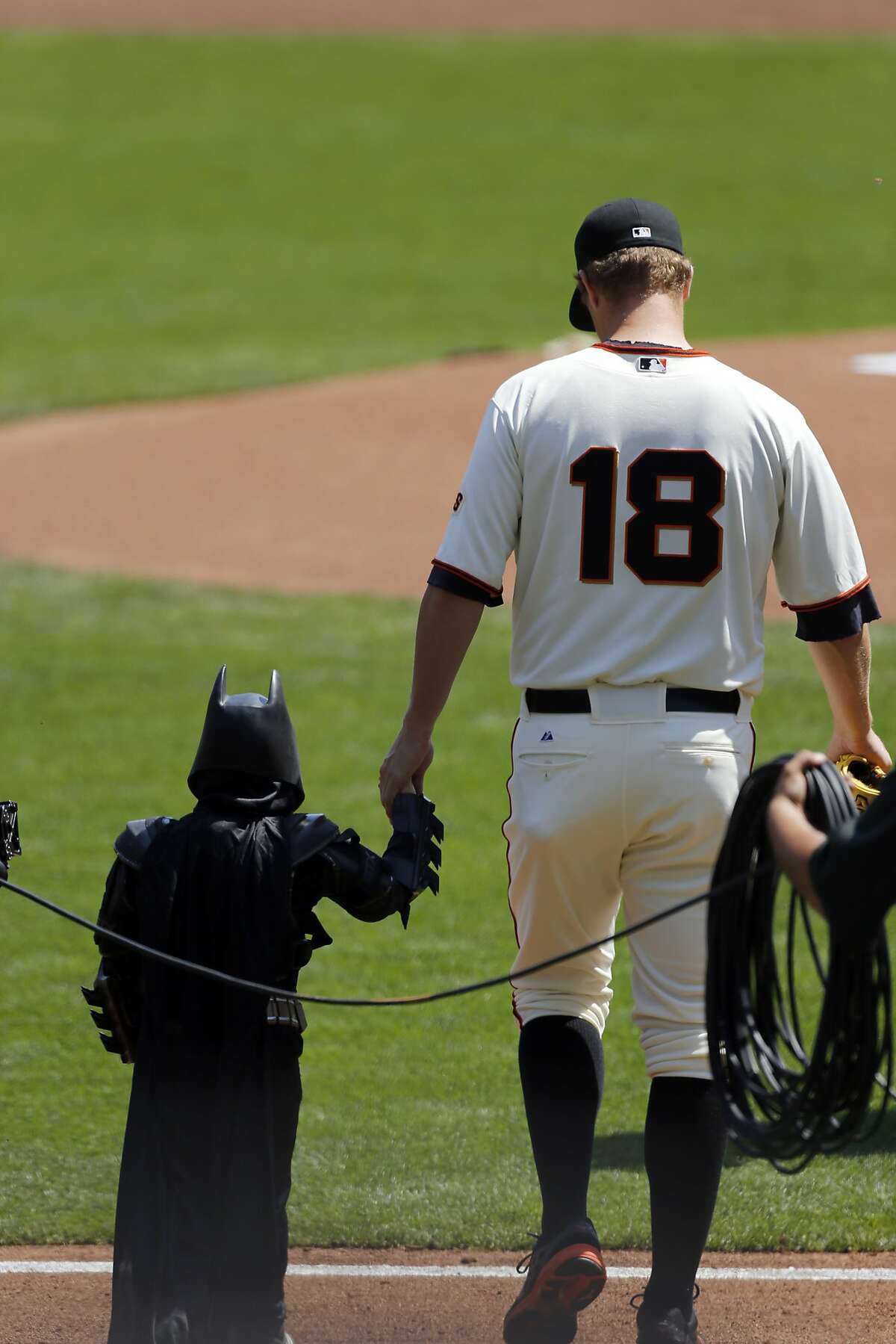 Giants pitcher Matt Cain walks Batkid to the pitcher's mound during the opening ceremonies as the San Francisco Giants prepare to take on the Arizona Diamondback during their home opener at AT&T Park on Tuesday April 8, 2014, in San Francisco, Calif.