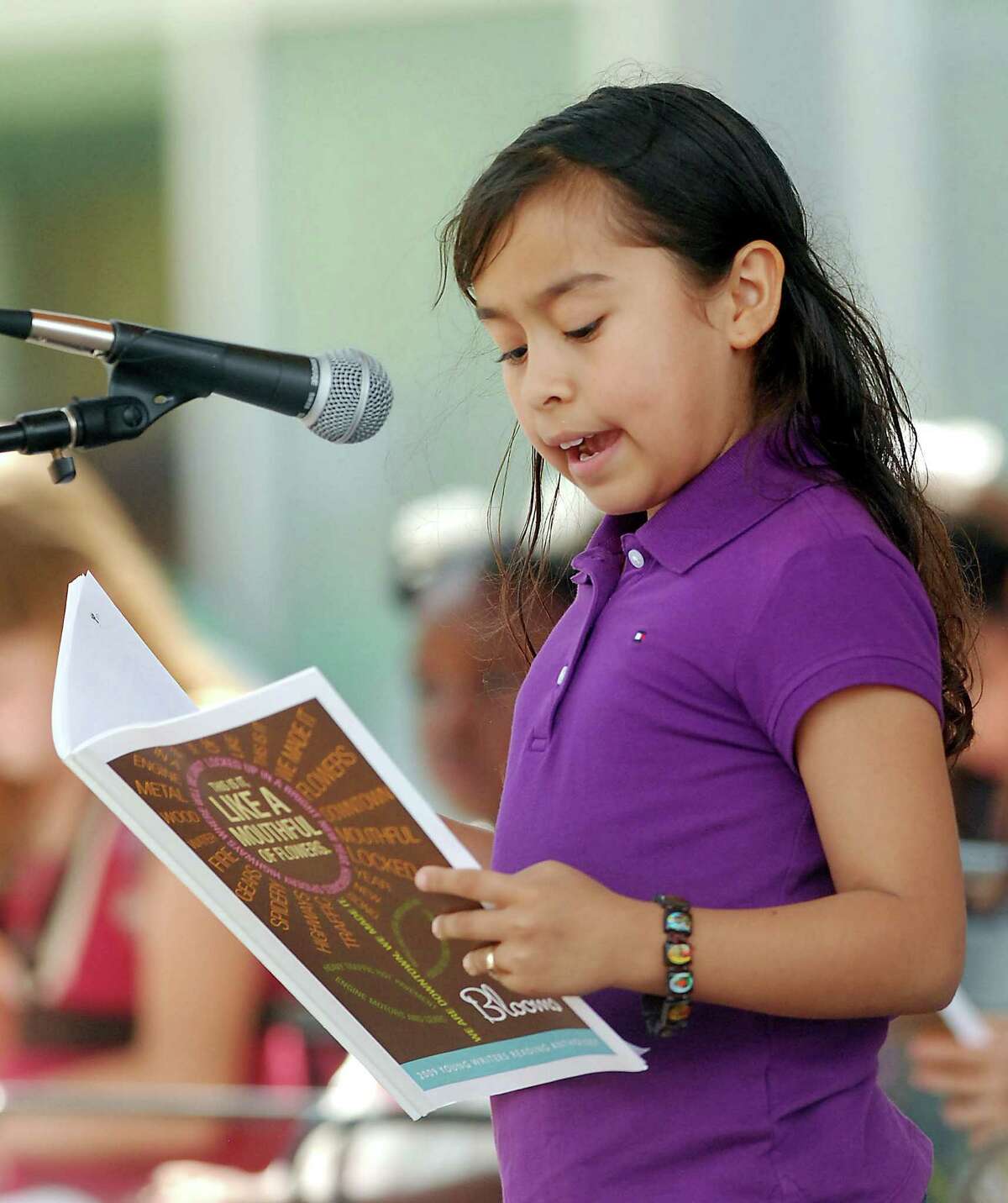 Jakeline Borja, a third-grade student from Sands Point Elementary School, reads an original work during 25th annual Young Writers in the Schools "Blooms" featuring works read by WITS students at Discovery Green Park Sunday May 03,2009. (Dave Rossman/For the Chronicle)