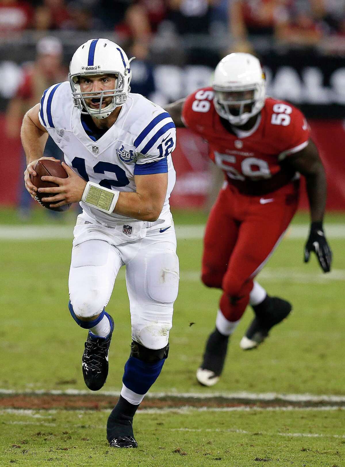 Indianapolis Colts' Andrew Luck (12) scrambles away from Arizona Cardinals' Marcus Benard (59) during the second half of an NFL football game Sunday, Nov. 24, 2013, in Glendale, Ariz. The Cardinals defeated the Colts 40-11. (AP Photo/Ross D. Franklin)